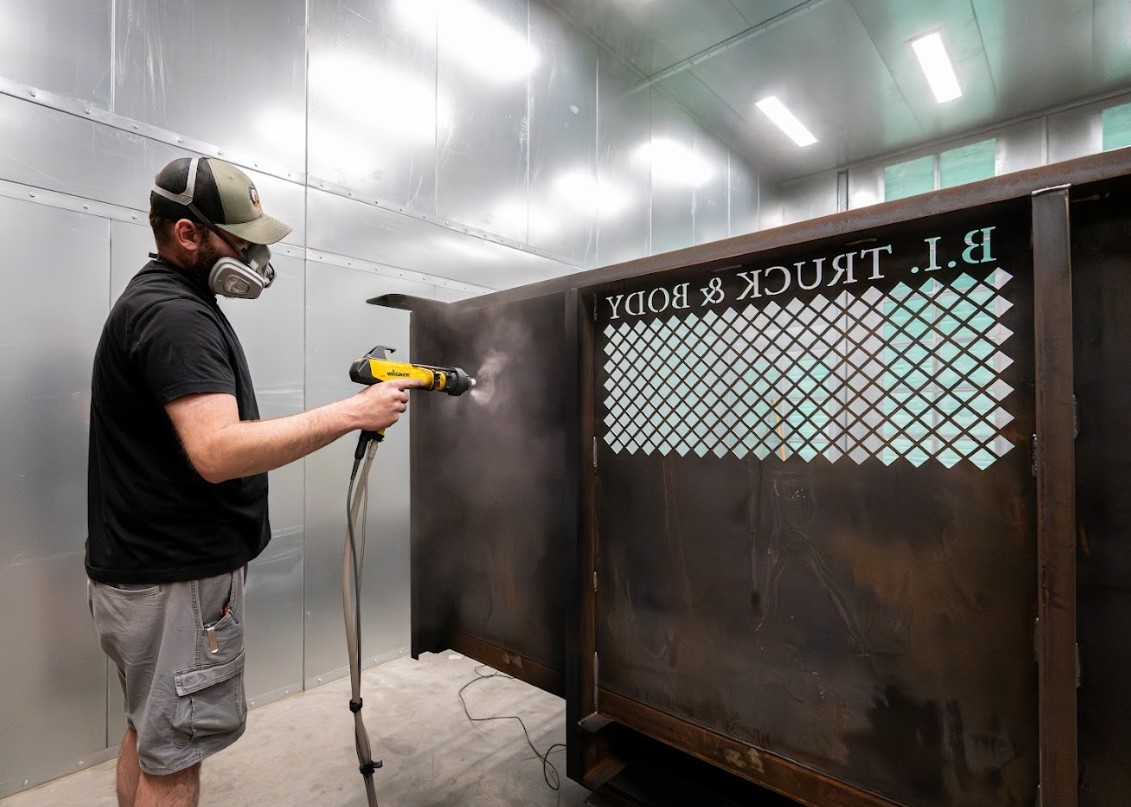 Technician applying powder coating to fabricated metal equipment